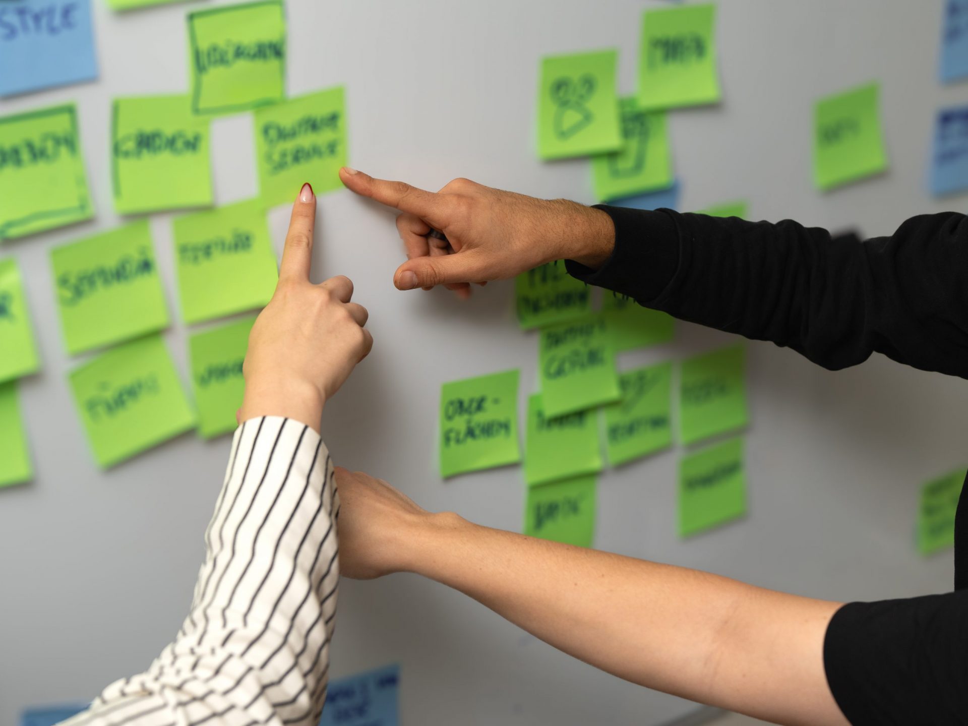 Three hands pointing at different post-it notes full of investor matchmaking program information